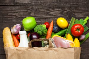 Full paper bag of different health food on rustic wooden background. Top view. Flat lay
