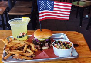 city barbeque meal with a drink and an american flag in the sandwich