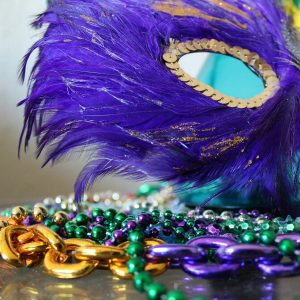Mardi Gras mask and beads with purple, yellow, and green