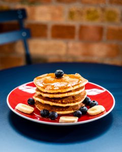 Brunch: stack of pancakes with bananas, blueberries, and syrup